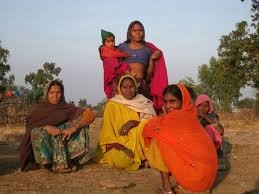 Brick By Brick, Grain By Grain, Gyarsi Bai And Team Stock Up Against Starvation  o	  •	The sun is about to set in Sunda village in Kishanganj block of Baran district that lies in southeast Rajasthan, on the border with Madhya Pradesh. A group of men and women dig the earth with spades on a small plot at one end of the village. They are Sahariyas, categorised by the government as a ‘primitive’ tribal group, hard at work on a self-initiated special project: A grain bank for their community.  •	The elders in the group describe why these families decided to do ‘shram daan’, volunteer and pool their labour, to build this grain bank. “It will enable us to not only guard against hunger but also give us freedom to choose our livelihood,” says Gyarsi Bai Sahariya, who works with the Jagrut Mahila Manch, a local non-government organisation, to organise tribal women in Baran. “Once it is there, we will neither have to worry about irregularities in public rations, nor will we have to depend for food on rich landlords,” she adds.   •	Gyarsi Bai, 49, was born into a poor landless family in Faldi village, a few kilometres from Sunda. She became active in organising the Sahariyas, especially women, after she came into contact with Charumitra Mehru and Moti Lal, activists of the Lok Jumbish programme, in 1992. She joined them in encouraging her community women to send girls to school.  •	Over the years she has mobilised Sahariyas to fight for their dues under the public ration system and mobilised them to join campaigns for Right to Information and employment guarantee. “Because many of us did not go to school, landlords try to cheat us out of our rights and our land. Even to get ration cards we have to sit in ‘dharnas’ (sit-in protest) in Jaipur and Beawar,” says Gyarsi Bai, who led community meetings in Sunda to plan the building of the grain bank.  •	Baran district, and particularly the Sahariya families living here – concentrated largely in the two blocks of Kishanganj and Shahabad – have come to national attention because of several hunger deaths over the last 12 years. The death of 47 Sahariyas because of starvation during the 2001 drought even triggered a Public Interest Litigation (PIL) in the Supreme Court on the right to food. Hunger deaths have been reported as recently as in 2004 and again three years ago in 2009.   •	It’s not like Baran is a completely arid area. In fact, the land here is fertile and supports two to three crops a year – mustard, cotton, wheat, or gram. More than tough terrain or harsh climatic conditions, it is the Sahariyas’ landlessness and feudal relations with primitive methods of production prevalent in these parts that have made them vulnerable to poor nutrition and starvation.    •	Sahariyas have been the focus of several government schemes since the 1960s but most are patchily implemented. They lost their traditional access to timber, gum, and mahua over time as large swathes of the deciduous forests in Baran disappeared. Of 1,030 land claims submitted in Kishanganj and Shahabad blocks since the Forest Rights Act 2006 came into force, the government has distributed land in 354 cases, a little over a third.   •	“Traditionally, we were not agriculturists. Over the years, we lost whatever small landholdings we had, to rich local landlords,” explains Gyarsi Bai, describing how Jat and Sikh landowners, who migrated to Baran from Punjab in the 1970s, gradually consolidated landholdings there. Hundreds of Sahariya families now work as ‘halis’, or bonded labourers, for the same landlords. They have worked without wages for years, in some instances over two and three generations.   •	This tribal group is entitled to 35 kilos of food grain every month under the government’s Antyodaya scheme. But many do not have ration cards and some complain of irregularity in getting rations on time. So, many have remained dependant on the landlords. “The landlord would give us 10-15 kilos of wheat once every few weeks, sometimes he would give us Rs 9-15 once a month for small expenses,” says Janaki Sahariya, who worked without wages for landlord Bittiya Singh in Sunda village for four years, against a bonded debt of Rs 20,000.   •	A struggle for freedom against these feudal practices began among the Sahariyas of Baran in November 2010 after the government agreed to release 16 families working as ‘halis’, who gave testimony at a ‘dharna’ for minimum wages under the MGNREGA at Jaipur. Since then 145 Sahariya families have been freed after the district administration waived off their bonded debt. Moreover, the state government has initiated a land survey in the district to redistribute land.  •	Today, the Sahariya families of Sunda village are making an effort to set themselves free from the curse of starvation, too. They say the setting up of the grain bank is an important intervention in this regard. It is necessary for them to be able to ensure they remain food secure irrespective of the state’s support or the landlords’ beneficence.  •	We have already pooled five quintals of wheat, which we have been collecting over the last year from a portion of the public rations that we are entitled to. It is stored at the anaganwadi temporarily. Over the next two to three weeks we will build the grain bank with our labour  •	says Babulal Sahariya, who worked without wages for 12 years for a landlord against a bonded debt of Rs 45,000.   •	In mid-January 2012, local landlords raised objections to their choice of land, claiming that it is forest area. However, records revealed that it was revenue land and the district officials have given the project a go-ahead.  •	The 40 Sahariya families of Chainpura, a tiny hamlet in Sunda, have chalked out in detail the norms that will govern the grain bank’s functioning. “Each household will contribute five kilos of wheat to the grain bank every month. Anyone would be able to take food grains as long as they replenish the stock adding a kilo for each month of borrowing,” elaborates Gyarsi Bai. Hemraj Sahariya and Swaroop Sahariya, both in their late teens, who are literate and were working as ‘halis’ until last year, have been appointed to keep basic accounts. “I can sign my name and count till 100,” Hemraj smiles, sitting at one corner of the 17 x 9 feet plot. Construction is now almost complete and the Sahariyas expect to start using the grain bank in a few days.  •	Says Gyarsi Bai, with satisfaction, “When we fled from the landlords’ farms, our biggest concern was where will we get food from now that no landlord will employ us. By pooling together five kilos of wheat each, we are no longer worried about going hungry.”   •	Following these families’ protracted struggle against being kept as bonded labourers, the Rajasthan government has entitled Sahariya families to 200 days of work under MGNREGA, twice the national norm. And they have begun some additional savings as well. “Some families have also started a ‘marriage fund’, putting together Rs 100 from their wages to tide over credit for consumption needs such as wedding ceremonies,” says Moti Lal, an activist with a local NGO, Sankalp, and a member of the bonded labour vigilance committee set up by the district administration last year. The women organised into three savings groups, and the men into four savings groups, pool in money from their MGNREGA and other daily wage work every week and deposit it in a bank account.   •	Freedom from bondage; freedom from hunger; freedom from malnutrition – Saharaiya women like Gyarsi Bai are looking for ways to break out of their “starved” existence. Setting up a grain bank is a great first step-vishnu ias